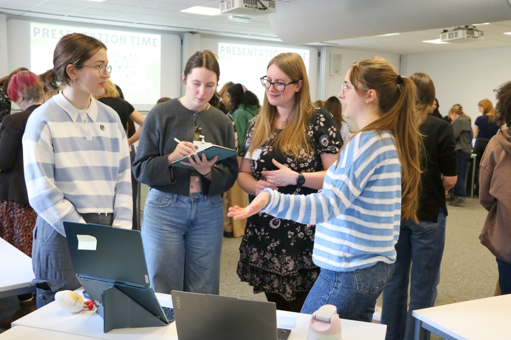 Sam, Lauren and two participants standing looking at a laptop screen